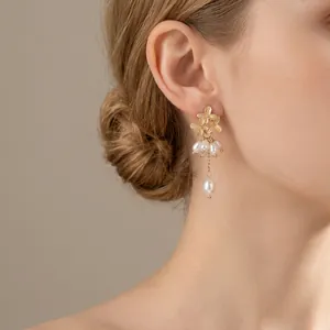 Elegant floral pearl tassel earrings in vintage gold finish shown on a female model