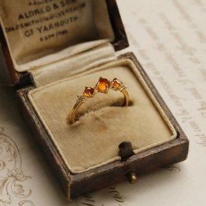 Vintage gold garnet ring with three orange gems in an antique jewelry box