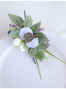Detail of the back side showing dual attachment clips on a purple and white silk boutonniere
