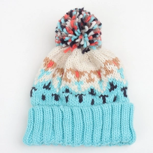 Detail of winter knit beanie with geometric rhombus pattern and multicolor faux fur pompom