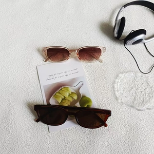 Flat lay of pinkish-brown and dark coffee oval sunglasses on textured white surface