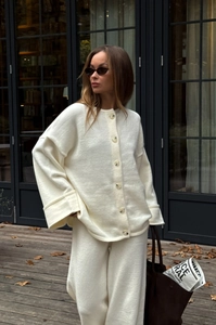 Detail of off-white knitted cardigan set featuring buttons and wide-leg trousers