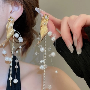 Detail of elegant gold flower leaf earrings with tassel pearls and sparkling zircon accents