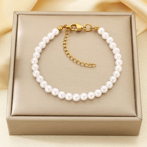Detailed view of white round pearls on an elegant champagne gold satin display surface