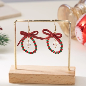 Detail of Christmas wreath earrings with red fabric bow and festive colored beads