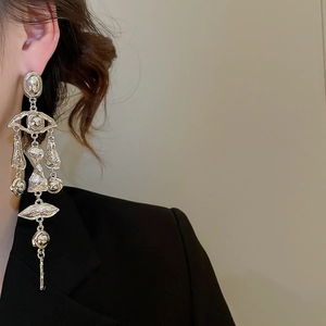 Macro detail of surrealist silver tassel earrings featuring abstract eye and lip charms