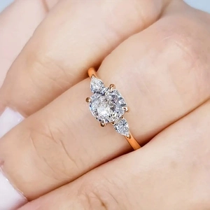 Close-up van roségouden ring met grote ronde witte steen en peervormige diamanten