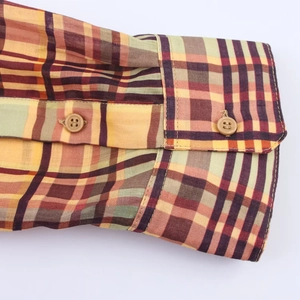 Détail du poignet d'une chemise à carreaux en coton avec des boutons marron élégants