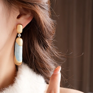 Dettaglio di orecchini vintage con smalto blu e cristallo su una modella