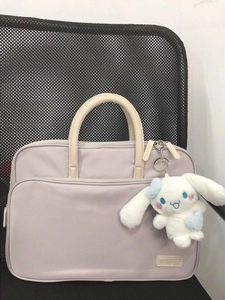 Lavendelfarbene Laptoptasche mit weißen Griffen und Schlüsselanhänger auf dem Bürostuhl