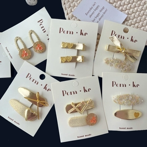 Bow and heart sequin hair clips set in gold and beige, professional flat lay on card