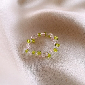Handmade elastic beaded ring with green and pink glass beads on silk fabric