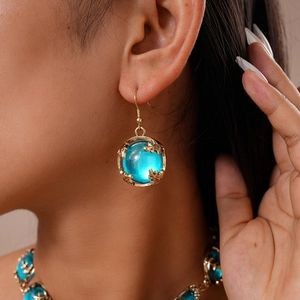 Vue détaillée des boucles d'oreilles rétro en résine bleu ciel avec bords dorés texturés