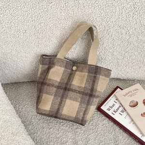 Close-up of brown checkered wool tote bag with bronze snap button and canvas handle