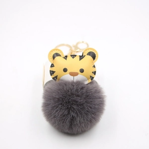 Close-up of cute cartoon tiger faux fur ball keychain with gold metal ring and spring clasp