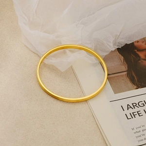 Minimalist gold plated titanium steel bangle featuring parallel grooved line patterns