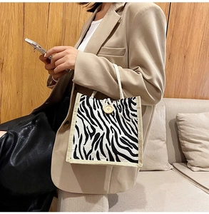 Detail of zebra stripe tote bag featuring woven cotton rope handle and wooden button accent