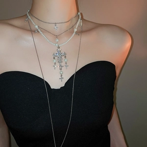 Detail of layered silver cross necklace with pearls and sparkling rhinestones on model