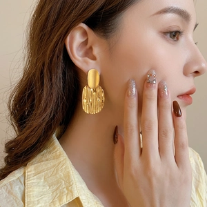Exaggerated gold textured metal earrings for women with irregular oval dangle design