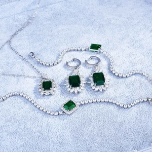 Macro detail of emerald-cut green crystal jewelry set with sparkling pavé cubic zirconia