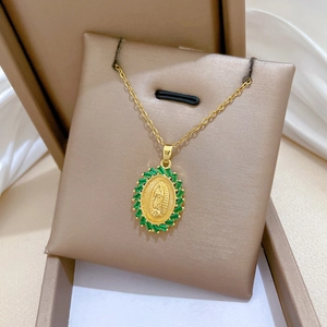 Close-up of gold tone necklace with green rhinestone inlaid oval pendant on jewelry box