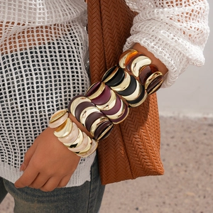 Dettaglio di braccialetti a segmenti in acrilico multicolore con montature dorate e design a scaglie