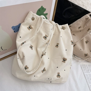 Close-up of corduroy tote bag featuring bear print and magnetic closure detail