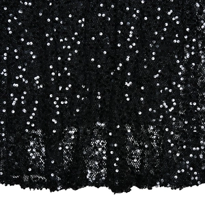 Dettaglio delle paillettes nere e della trama in rete sull'abito da sera con schiena scoperta