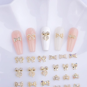 Detail view of 3D alloy bow nail charms with pearls and rhinestones on white ceramic