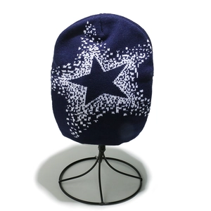 Detail of navy knit beanie with white star pattern on a black metal hat stand