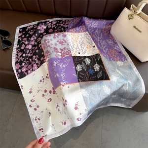 Carré en soie à motif floral patchwork sur un canapé en cuir avec sac à main et lunettes