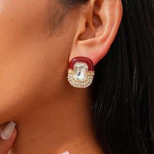 Close-up of vintage red enamel earrings with rectangular crystal on a model ear
