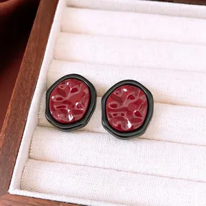 French vintage dark red resin earrings with irregular gold edges in a jewelry box