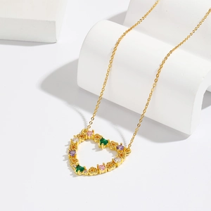 Gold hollow heart pendant necklace with colorful cubic zirconia on a white platform