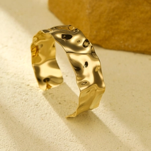 Detailed macro view of wide gold open cuff bracelet with irregular wrinkled metal texture