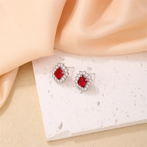 Bowtie silver earrings with red square zircon and sparkling stones on white stone