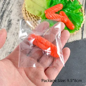Modèle de mini saucisse réaliste en PVC pour porte-clés présenté à la main sur fond vert