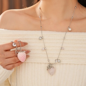 Close-up of heart-shaped strawberry pendant necklace with pearls on a model wearing a sweater