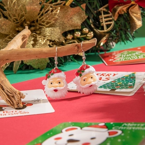 Close-up of cute Santa Claus earrings hanging on a branch with festive holiday background