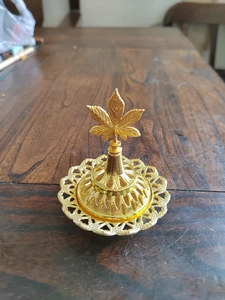 Detailed close-up of a golden hollow incense burner with a maple leaf lid handle decoration