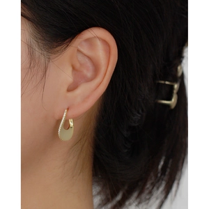 U-shaped gold earring with sparkling white zircons on a female model closeup