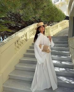 Detail of V-neck lace dress with ruffle cuffs and a woven hat on marble stairs