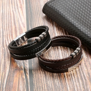Detail of black and brown multi-layer braided leather bracelets with stainless steel clasps