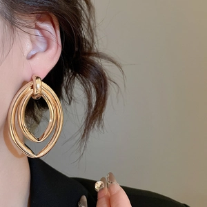 Détail d'un mannequin portant des boucles d'oreilles ovales dorées à trois couches