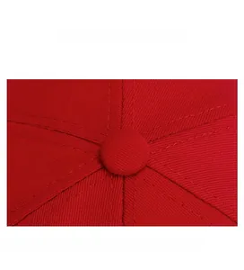 Macro shot of red cotton baseball cap top showing six-panel stitching and button detail