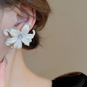 Close-up of creamy white acrylic flower earring with pearl finish and zircon center