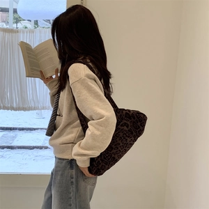 Dettaglio della borsa tote leopardata abbinata a un maglione grigio in un ambiente accogliente