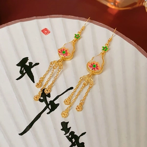 Detail of gold tassel earrings featuring lotus patterns on a white folding fan base