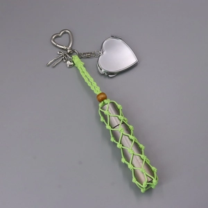 Dettaglio dello specchio a cuore argento e porta rossetto in borsa a rete verde portachiavi