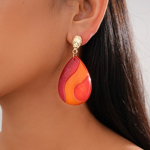Detail of red marble acrylic teardrop earrings with hammered gold stud on a model